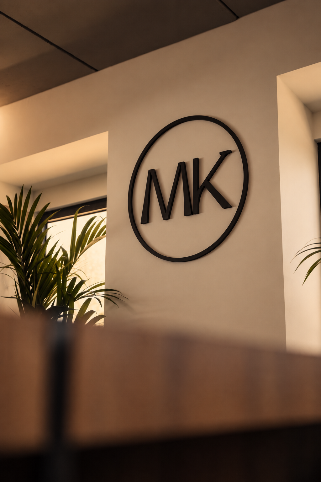 Logotipo MK de Molokai en la pared de la oficina, junto a una planta