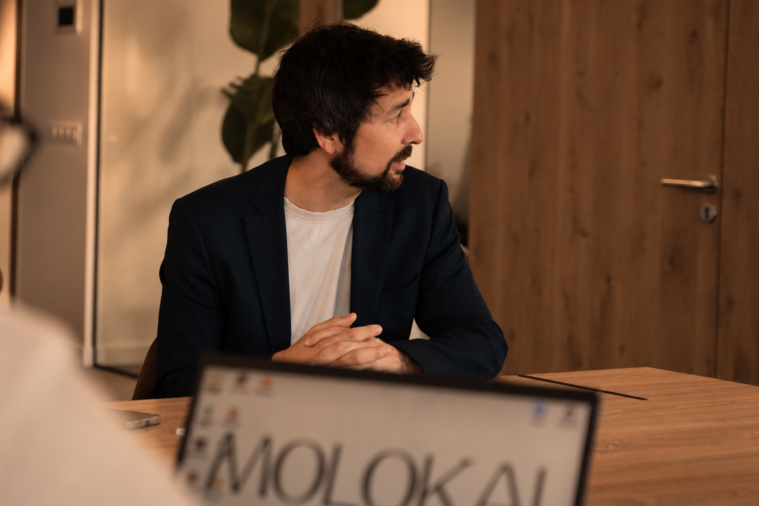Miembro del equipo de Molokai en una reunión, con el portátil MOLOKAI en primer plano