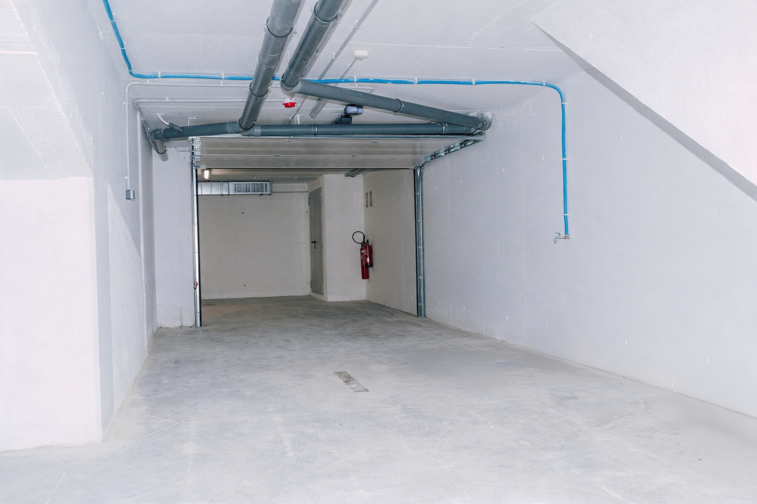 Gaia — parking con la puerta de garaje seccional abierta